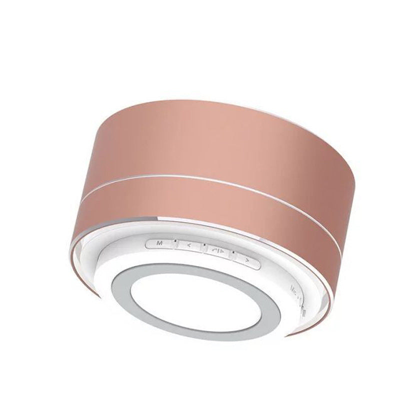 Rose gold wireless Bluetooth speaker with white base, circular design, and integrated control buttons for music playback.