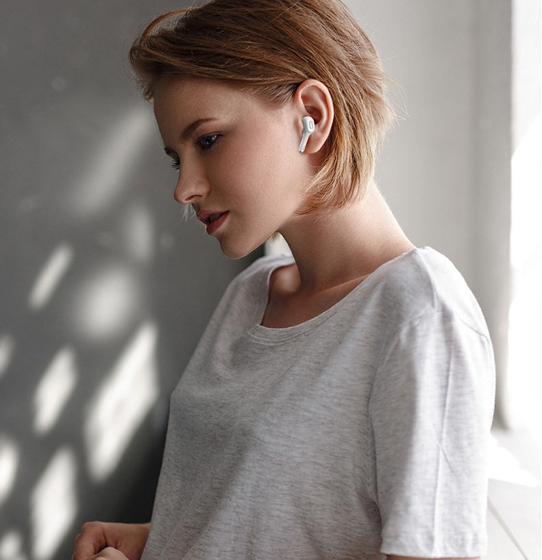 Woman wearing sleek white wireless Bluetooth earbuds, enjoying music in a softly lit indoor setting, showcasing a modern and minimalist lifestyle.

