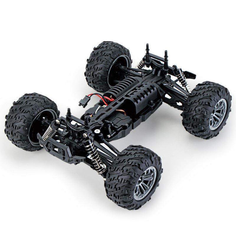 RC car chassis detail—independent suspension, coil-over shocks, large tires, and centered electronics layout.