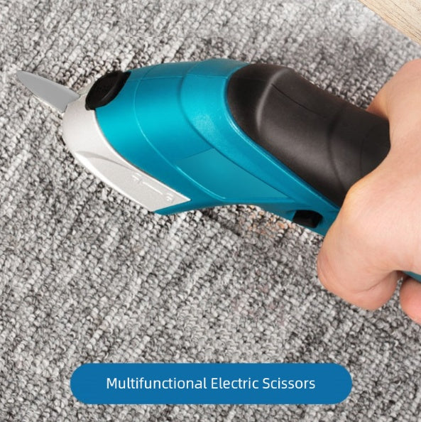 Hand using a blue and black multifunctional electric scissors to cut through a gray carpet, demonstrating the tool's precision and ease of use on thick fabric.