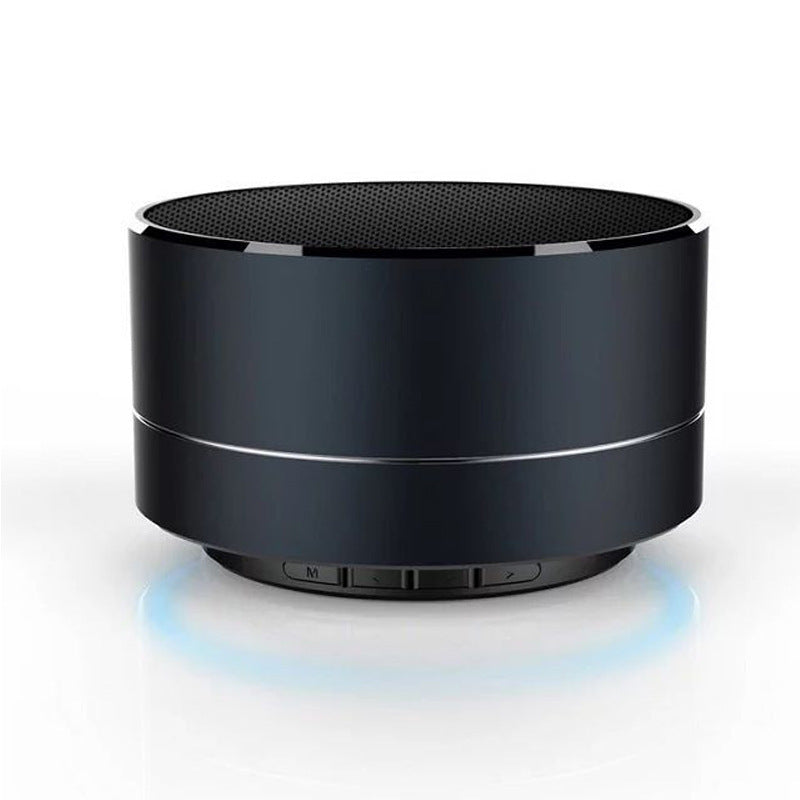 Modern black wireless Bluetooth speaker with sleek metallic finish and control buttons, emitting a subtle blue LED glow on a white surface.