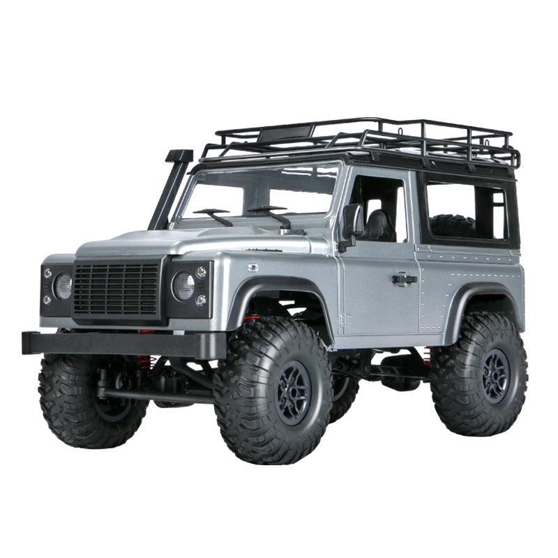 Angled front-side shot of silver RC Defender with roof rack and rugged tires.