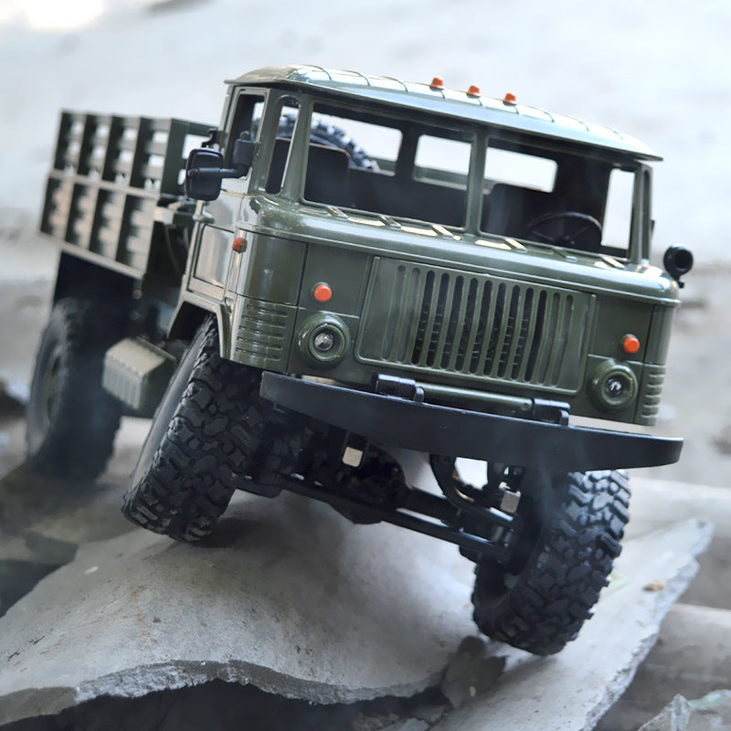 Green military RC truck climbing over rough concrete terrain