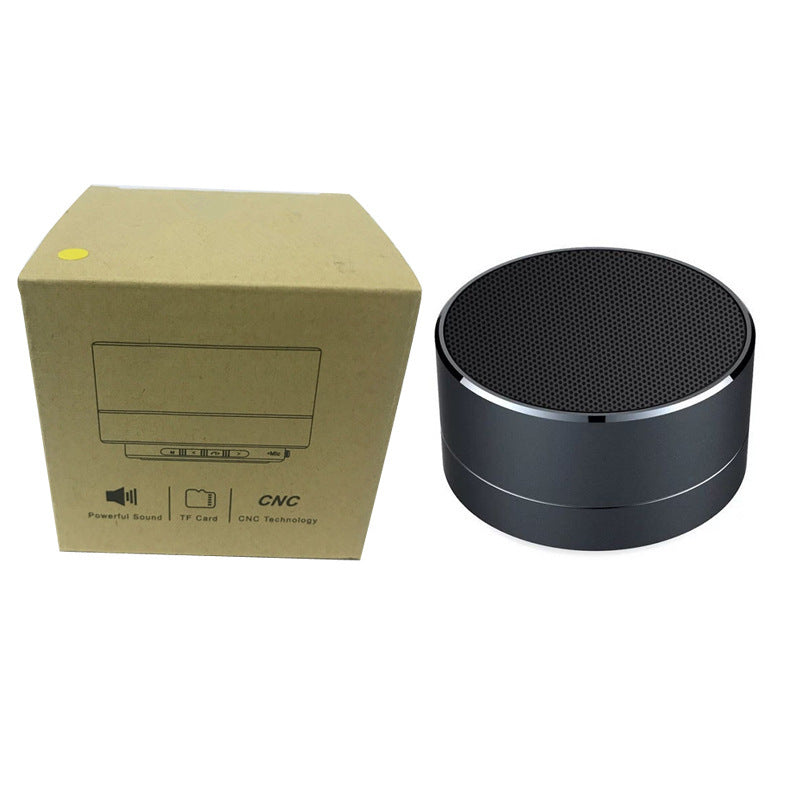 Black round mini Bluetooth speaker with precision CNC aluminum body, shown alongside its minimalist cardboard packaging featuring icons for powerful sound, TF card support, and CNC technology.
