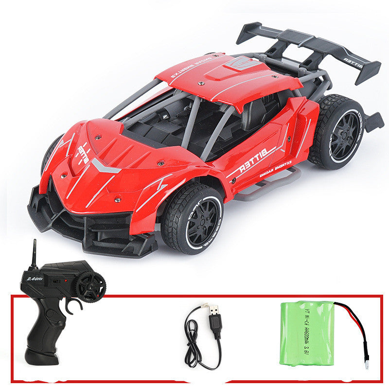 Red toy car with black details and remote control, charger, and battery on a white background