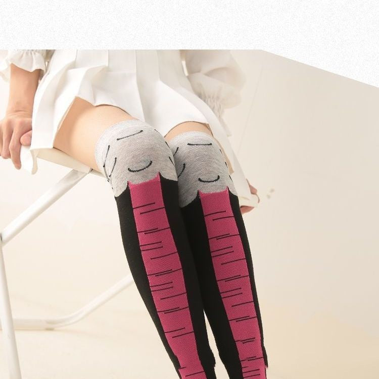 Close-up of a person sitting in a white skirt wearing playful knee-high socks designed to look like pink bird legs, with gray tops featuring feather details and black sides.