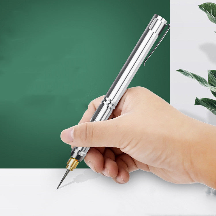 A hand holding a silver electric engraving grinder lettering pen with a detailed engraving tip.