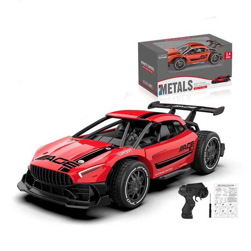 Red toy race car with black details, remote control, and packaging on a white background