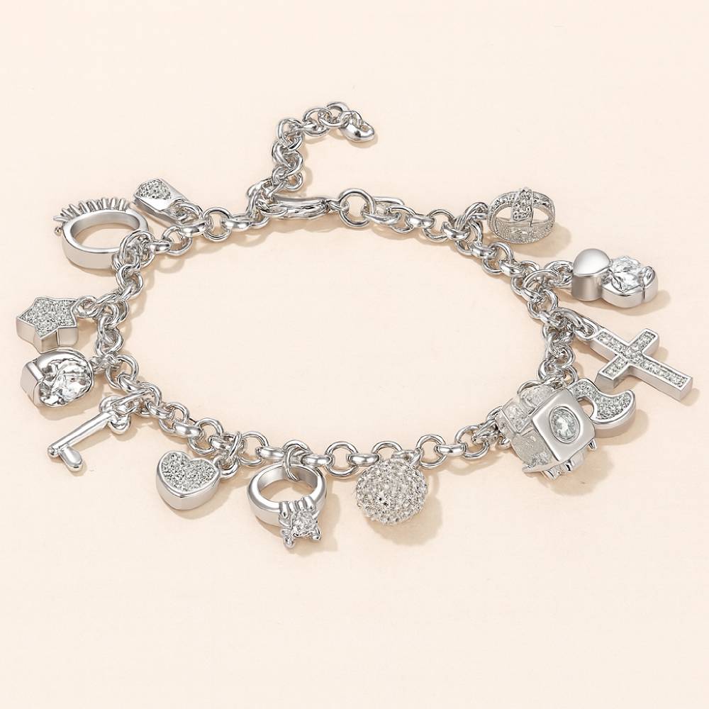 Silver charm bracelet with various charms on a light beige background