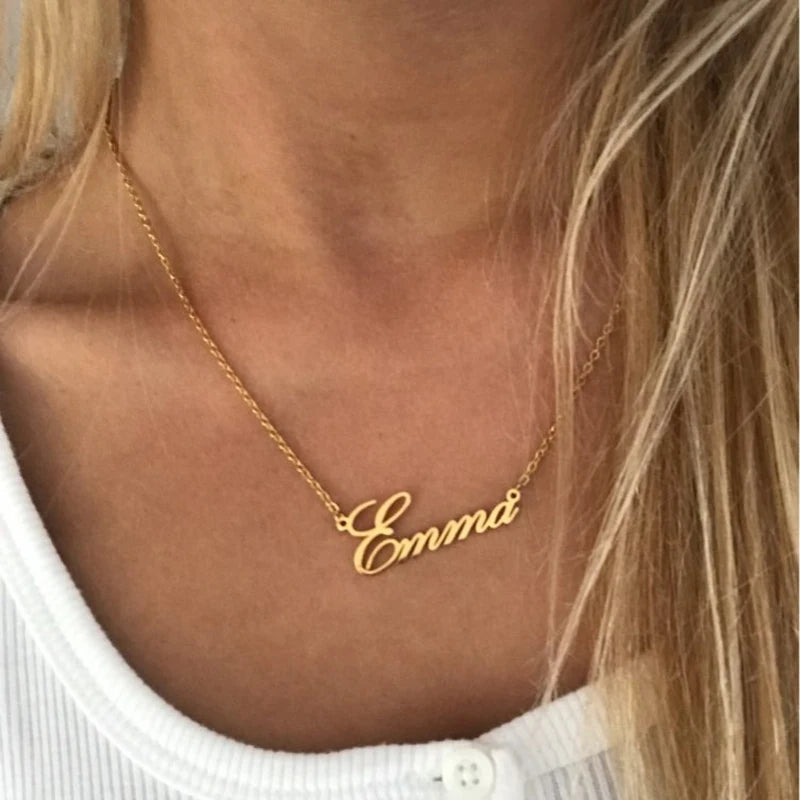Gold necklace with 'Emma' pendant on a person wearing a white top.