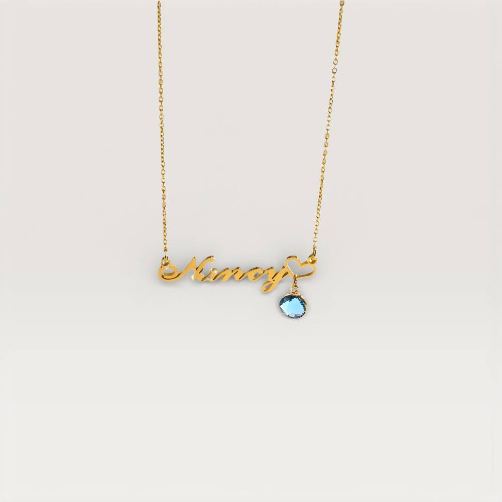 Gold necklace with 'Nina' and a blue gemstone on a light gray background
