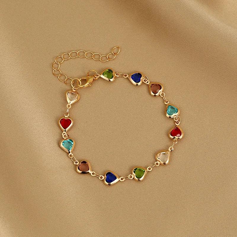 Gold bracelet with colorful heart-shaped beads on a beige fabric background