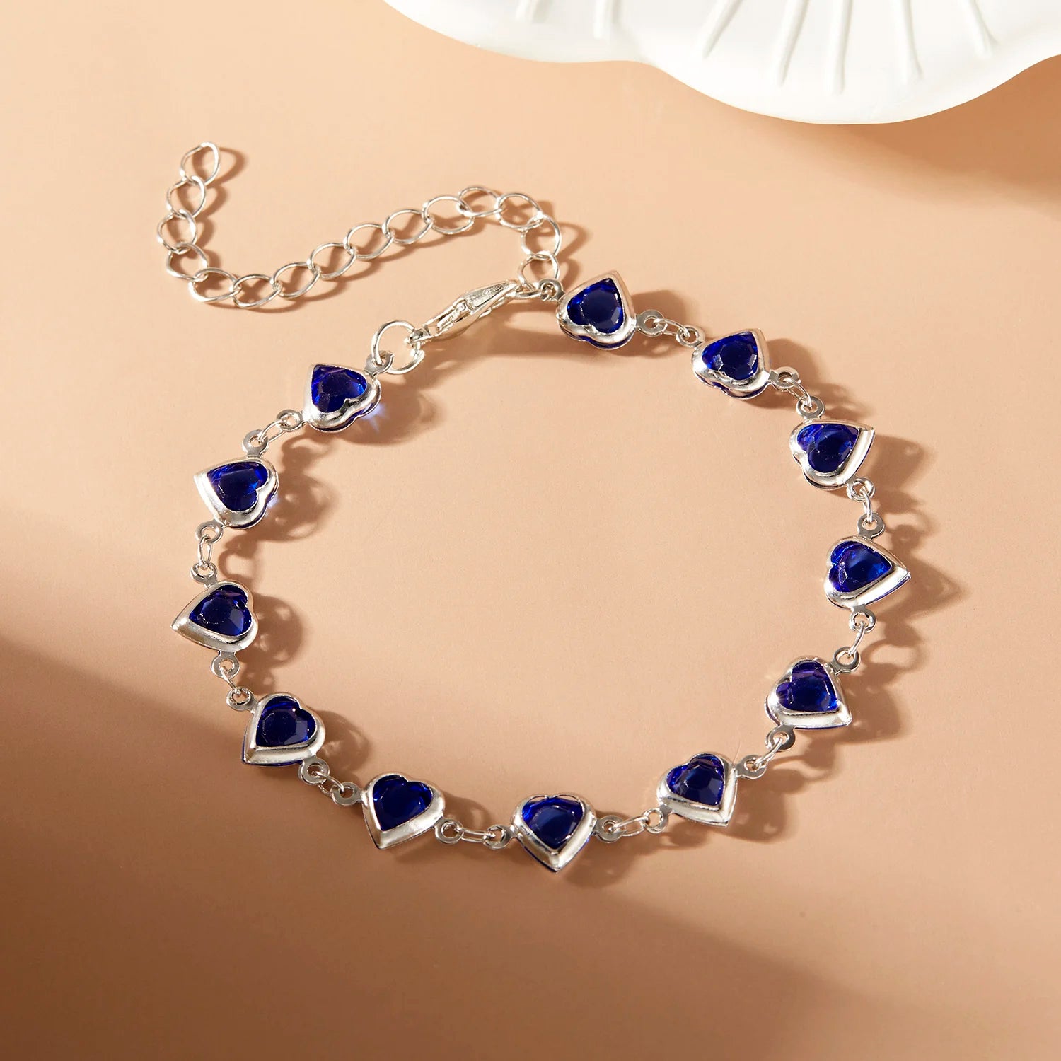 Silver bracelet with blue heart-shaped stones on a beige background
