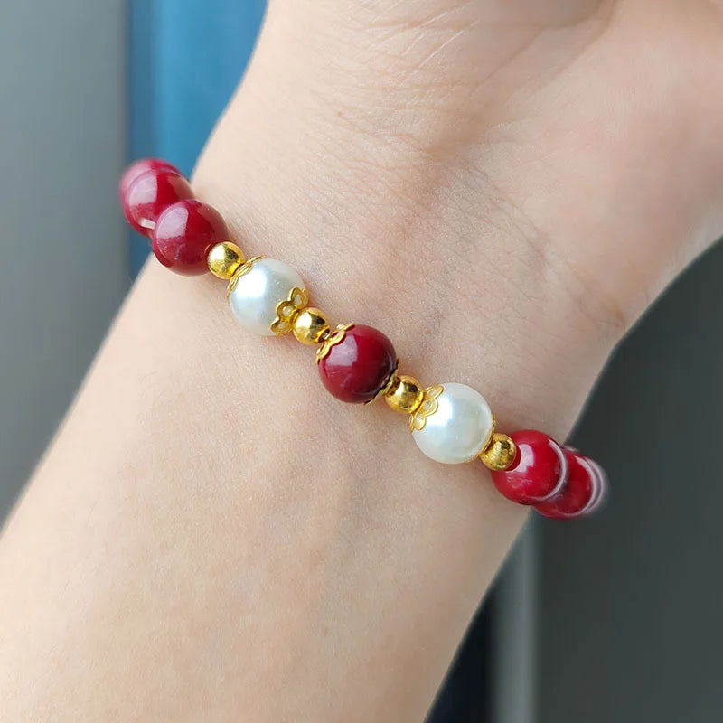Bracelet with red and white beads on a wrist against a neutral background