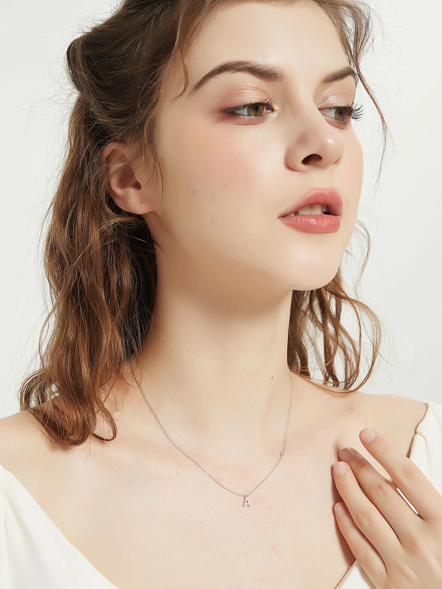 Woman wearing a delicate necklace on a plain background