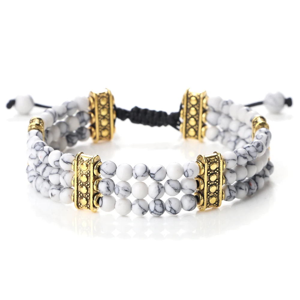 Multi-layered bracelet with white beads, gold accents, and black cord on a white background