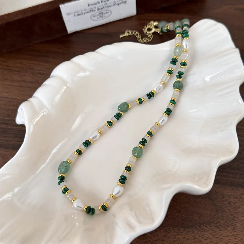 Necklace with green and gold beads on a white dish