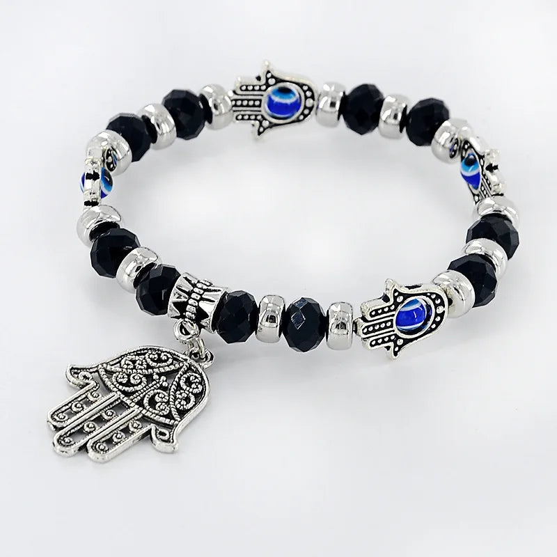 Bracelet with black beads, silver Hamsa charms, and blue stones on a white background