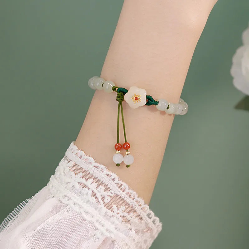 Bracelet with floral design on a wrist against a green background