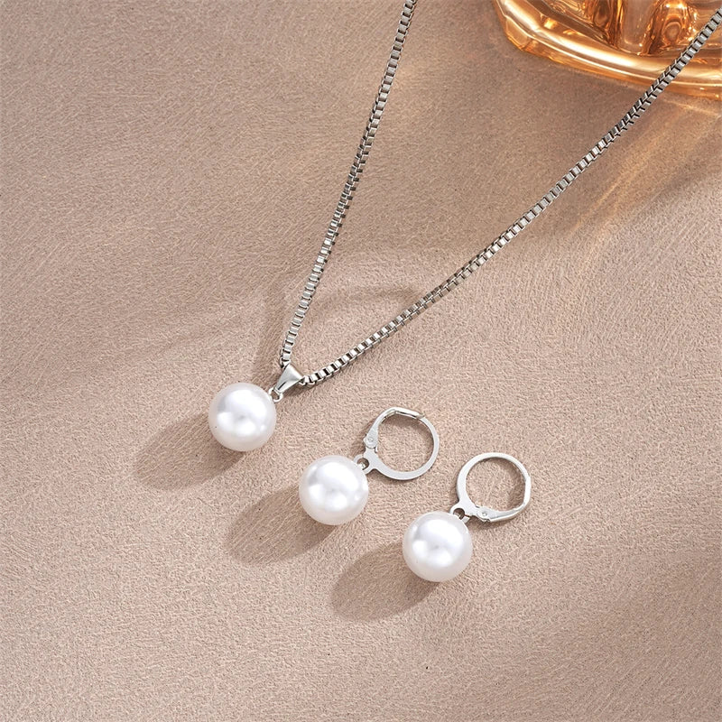 Pearl necklace and earrings set on a beige surface
