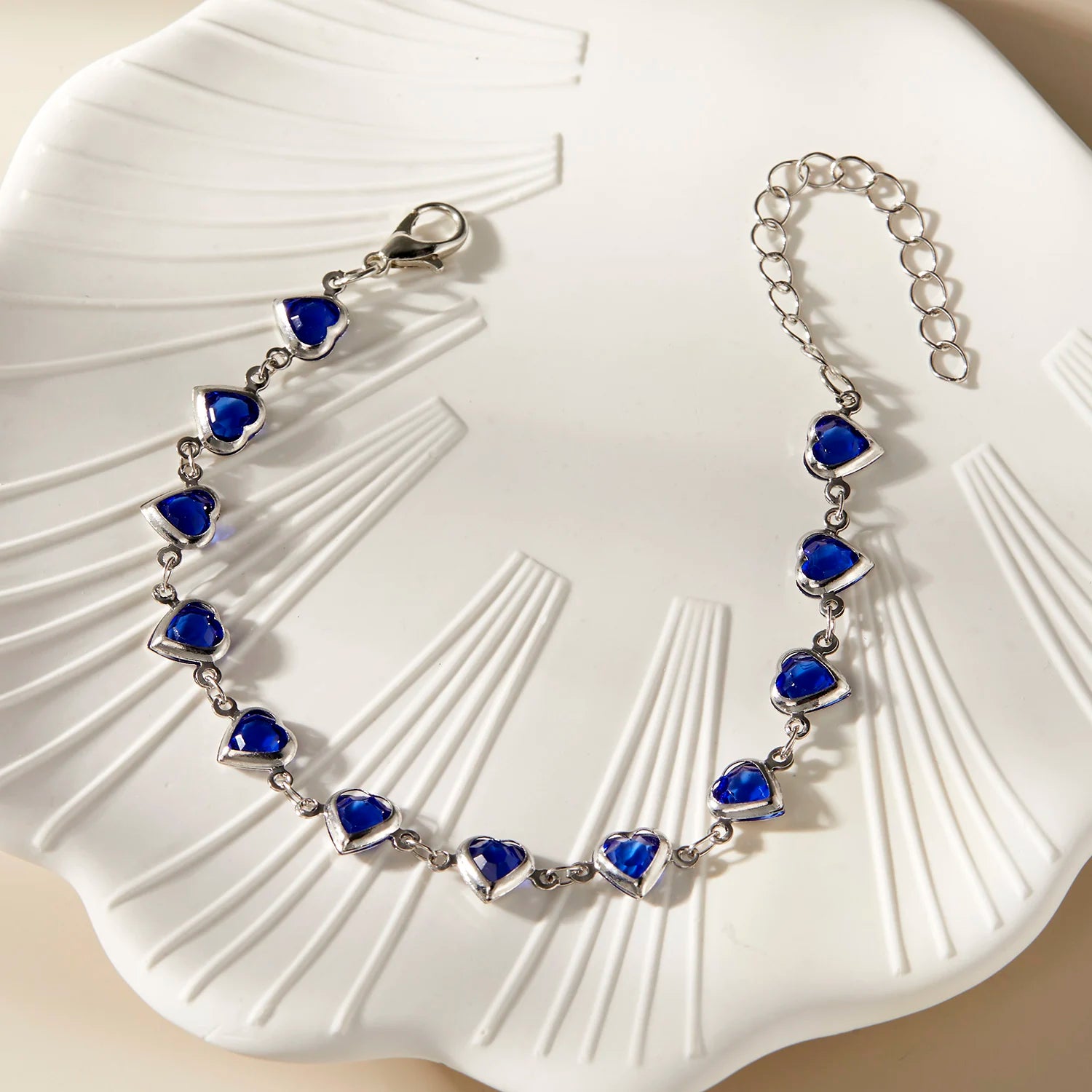 Silver bracelet with blue heart-shaped stones on a white shell