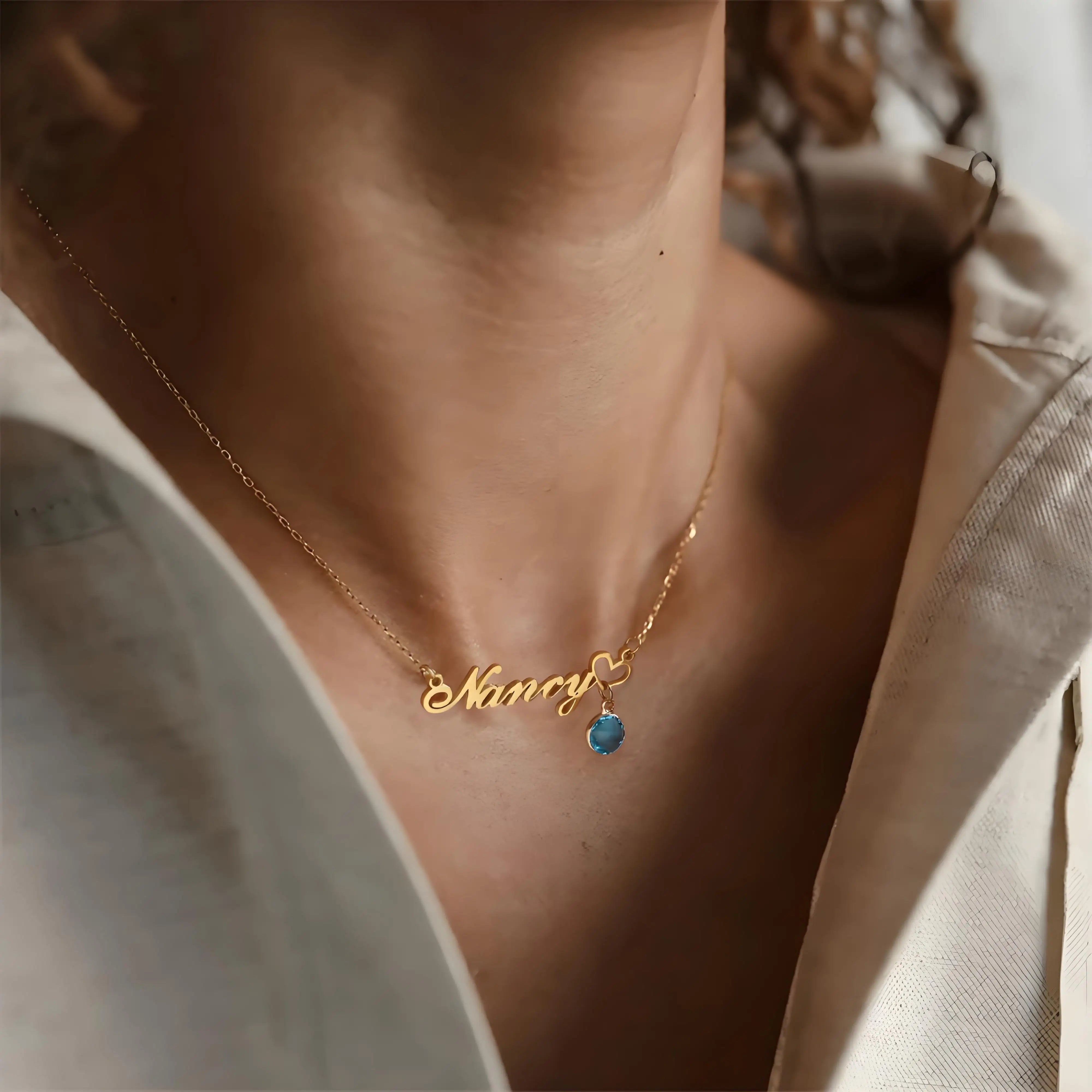 Gold necklace with 'Nancy' pendant worn by a person