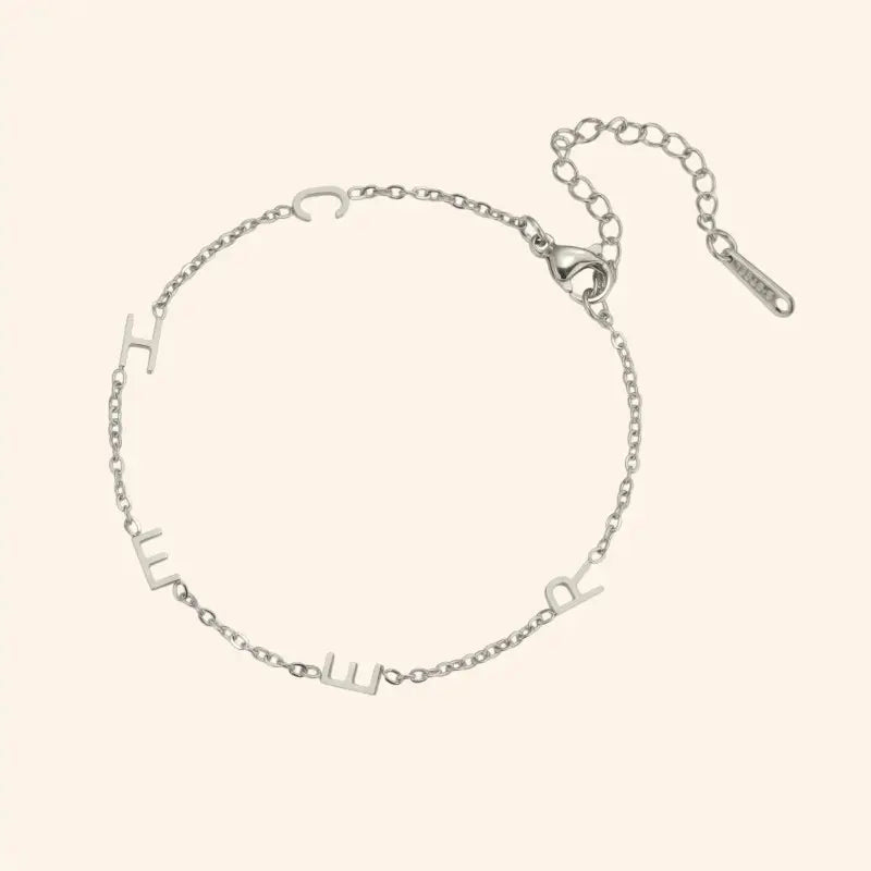 Silver bracelet with letter charms on a white background