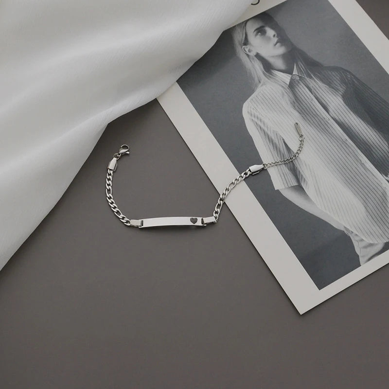 Silver chain bracelet on a gray surface with a black and white photo of a person in the background.