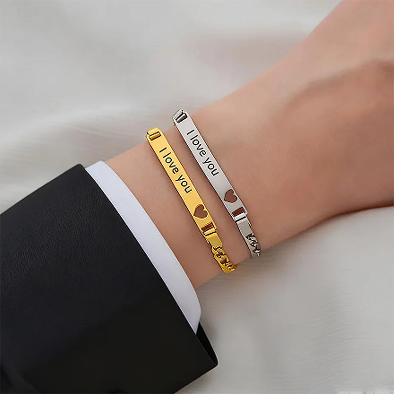 Two bracelets, one gold and one silver, on a wrist with 'I love you' text.