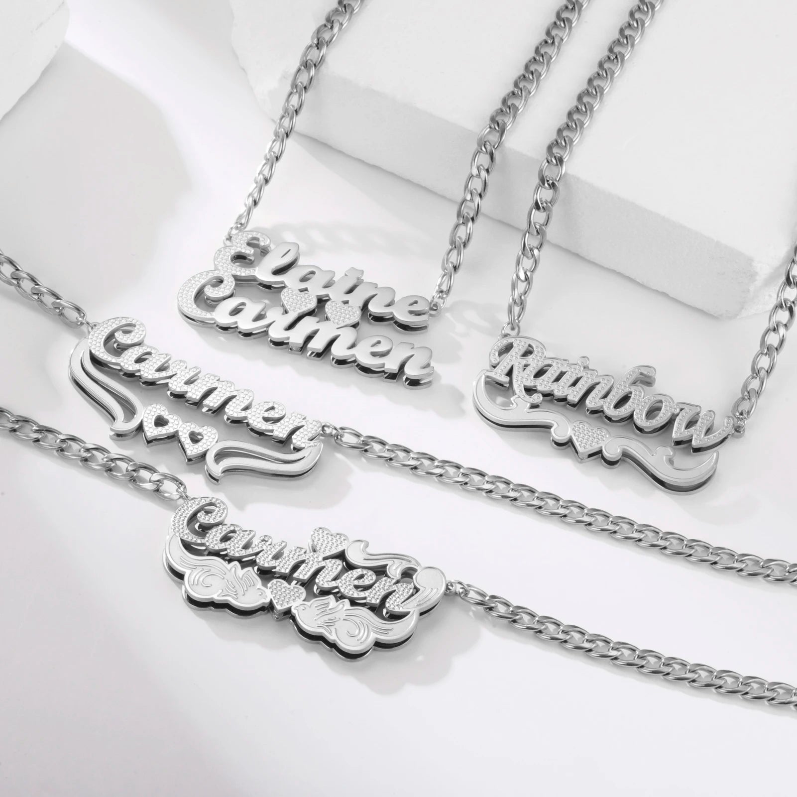 Silver necklaces with engraved names on a white background