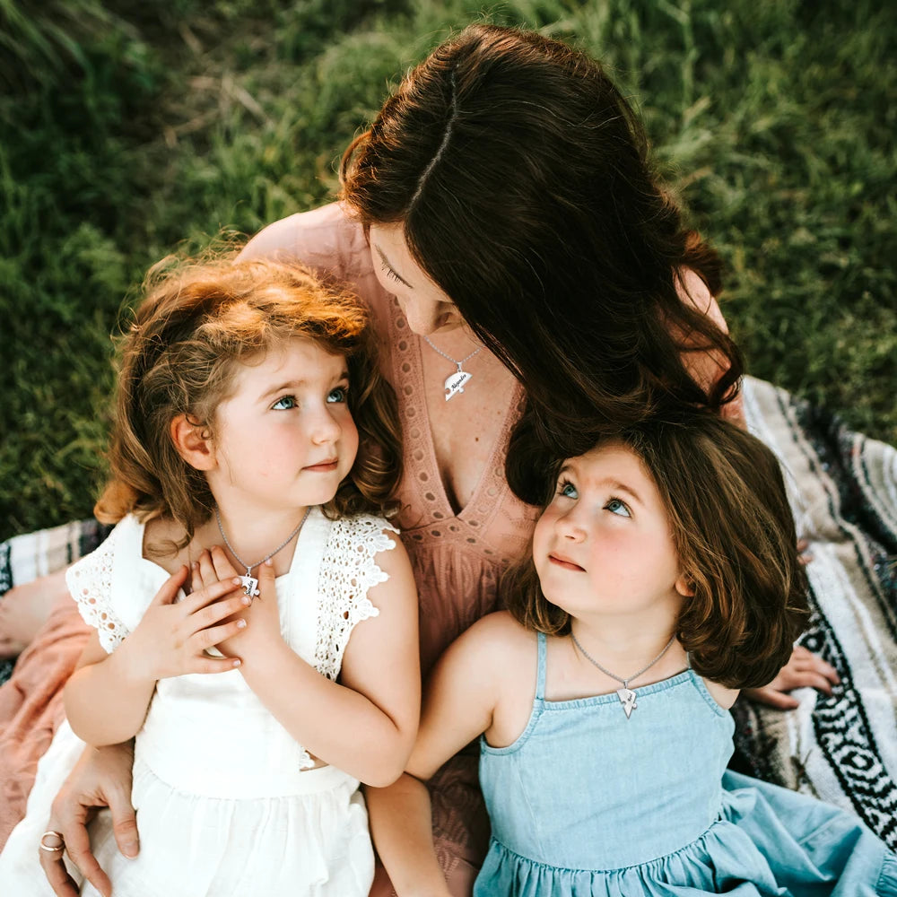 Woman with two young children outdoors on a grassy background