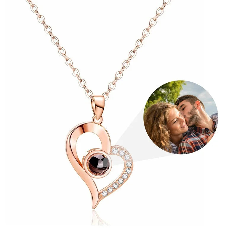 Rose gold heart-shaped necklace with a dark gemstone and small diamonds, inset with a photo of a couple.