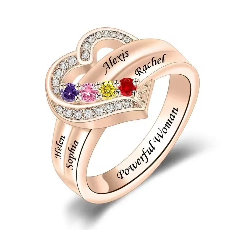 Heart-shaped ring with engraved names and colorful gemstones on a white background