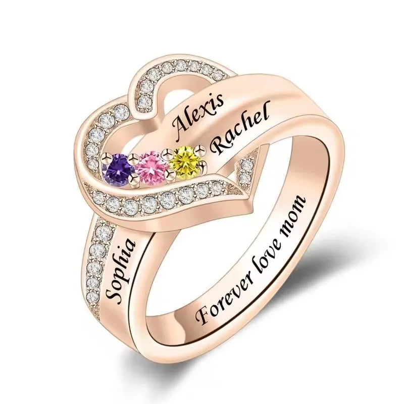 Heart-shaped ring with engraved names and colorful gemstones on a white background