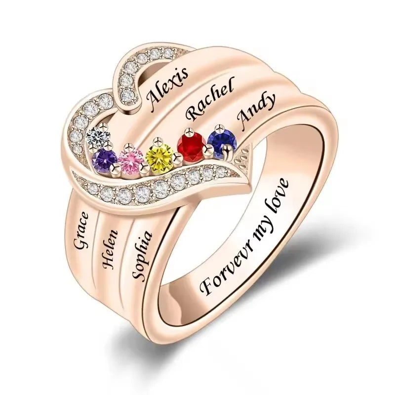 Heart-shaped ring with engraved names and colorful gemstones on a white background