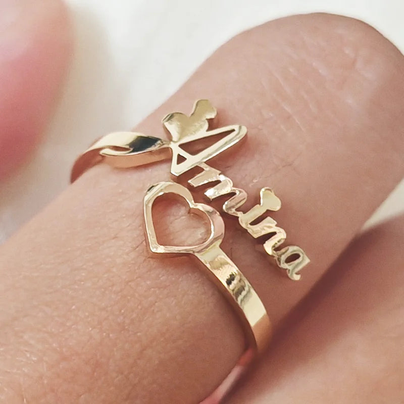 Gold ring with 'Amour' on a finger against a neutral background