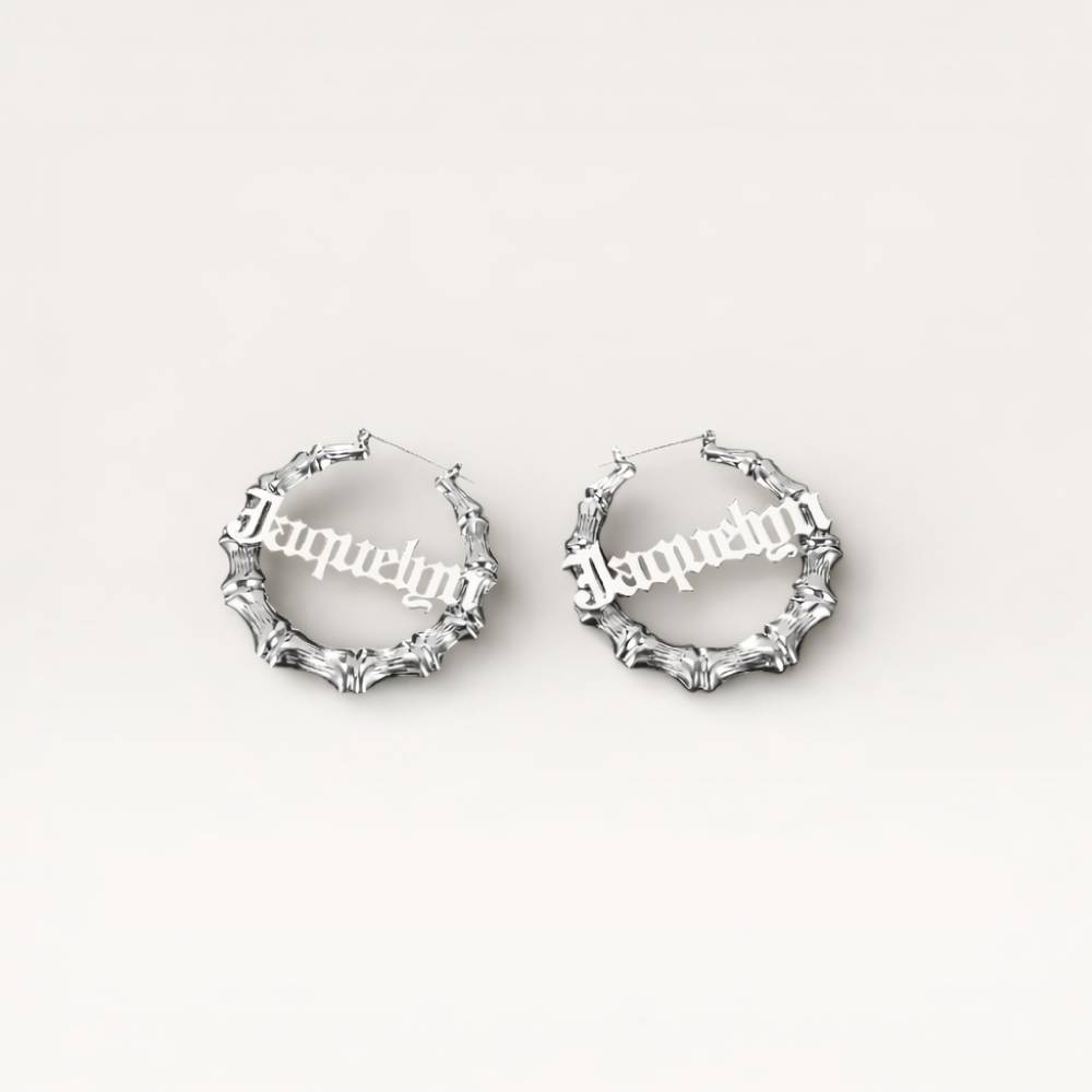 Pair of silver hoop earrings with engraved text on a light gray background