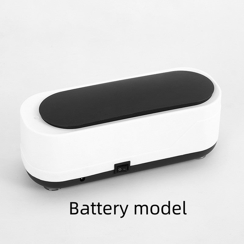 Compact ultrasonic cleaner with white body and black lid, labeled as “Battery model,” featuring a central power switch on a white background.