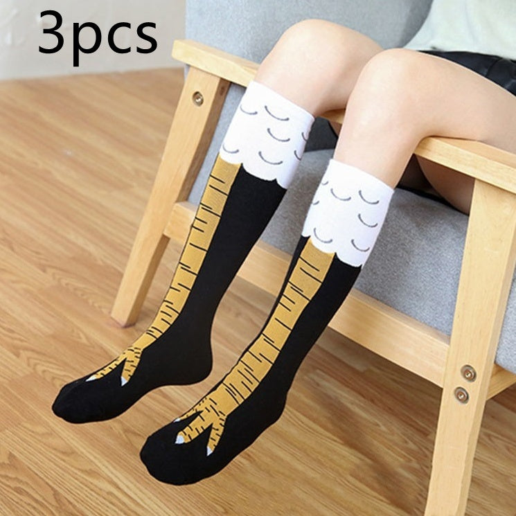 Person sitting on a wooden chair wearing a pair of novelty knee-high socks designed to resemble bird legs with yellow talons and white feather tops; text 