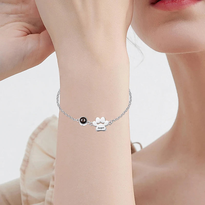 Silver bracelet with a black bead and white bow design on a person's wrist.