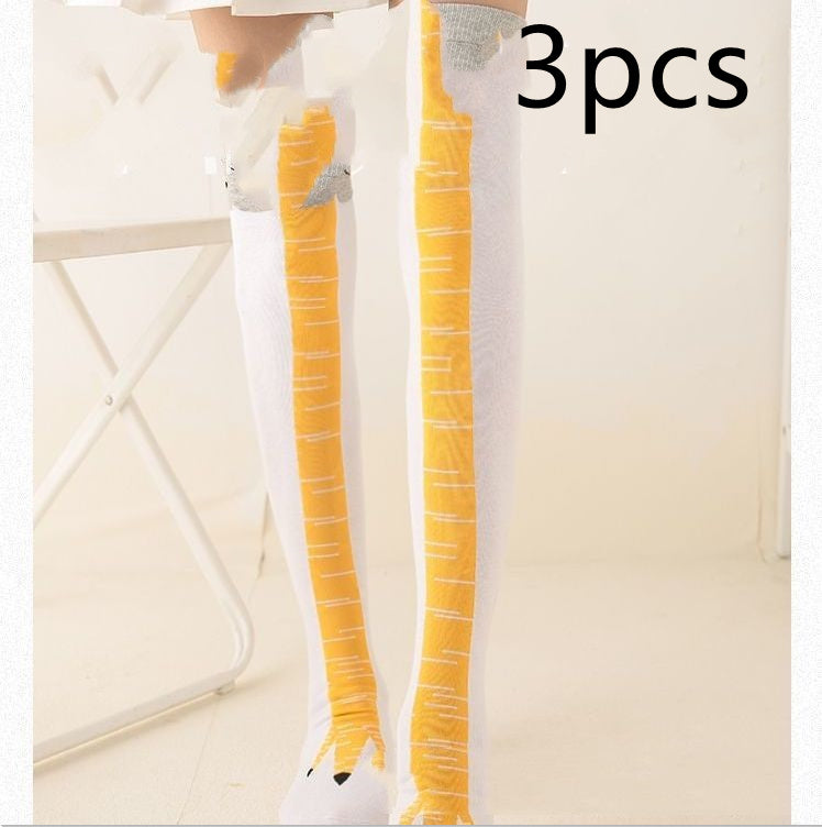 Model standing indoors wearing novelty white knee-high socks with yellow bird-leg design and grey feather-like tops; black 