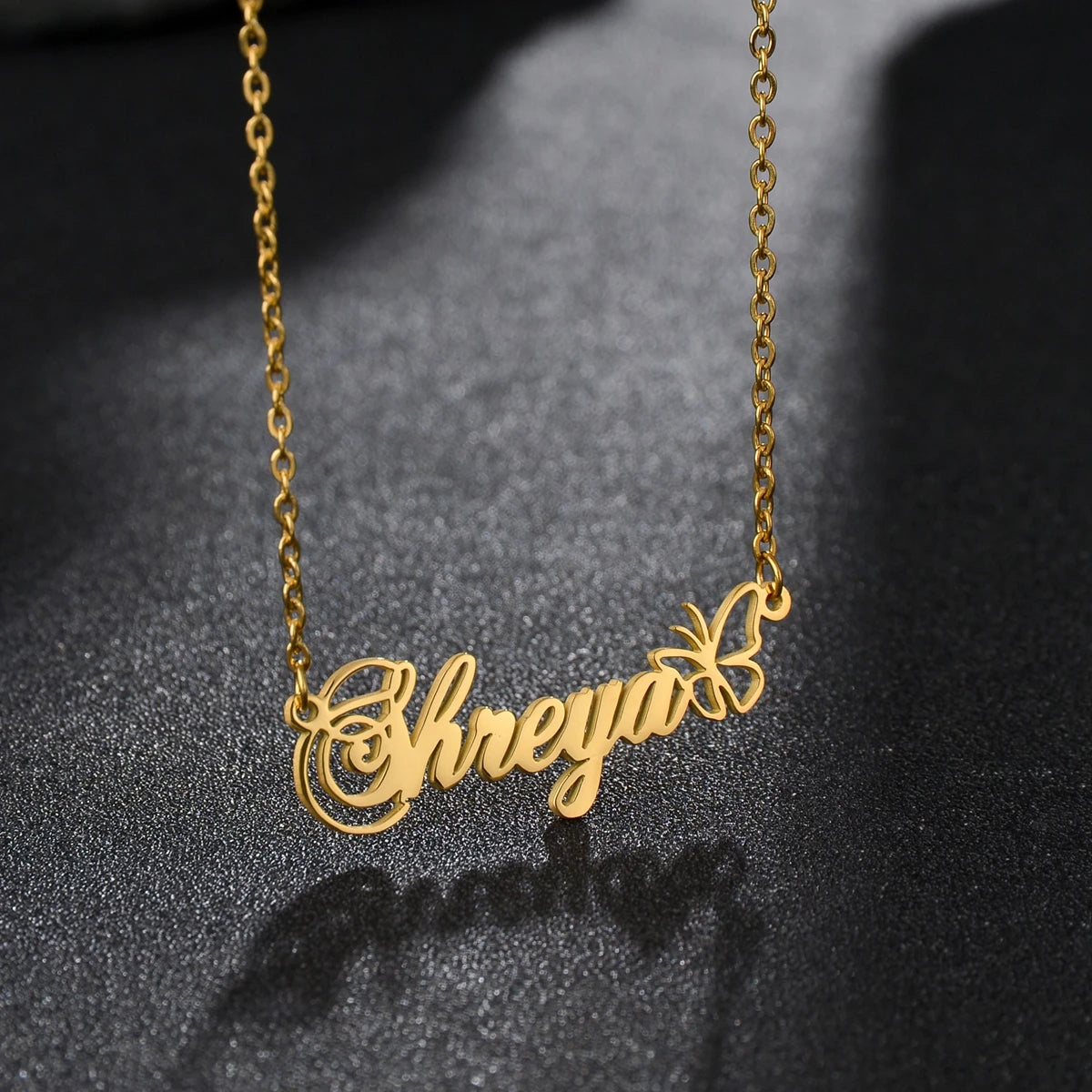 Gold name necklace with 'Shreya' on a dark textured background