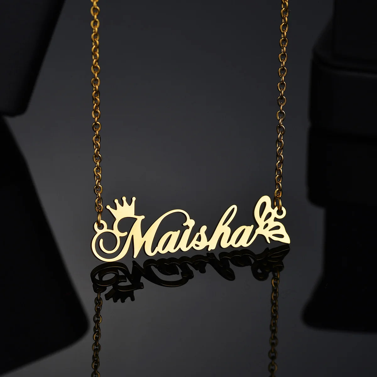 Gold necklace with 'Maisha' pendant on a dark background