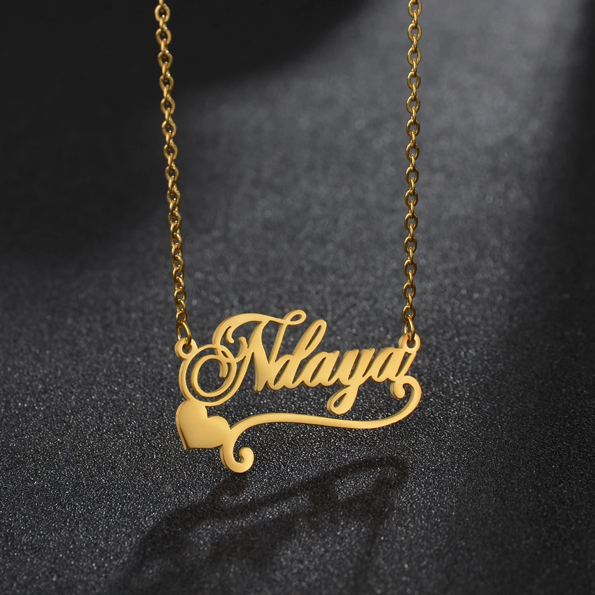 Gold necklace with 'Ndaya' pendant on a dark background
