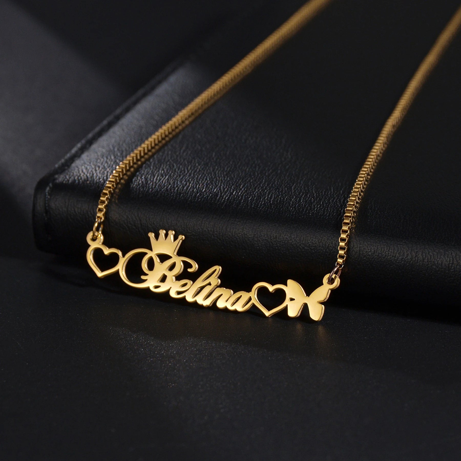 Gold necklace with 'Belina' and decorative elements on a black background