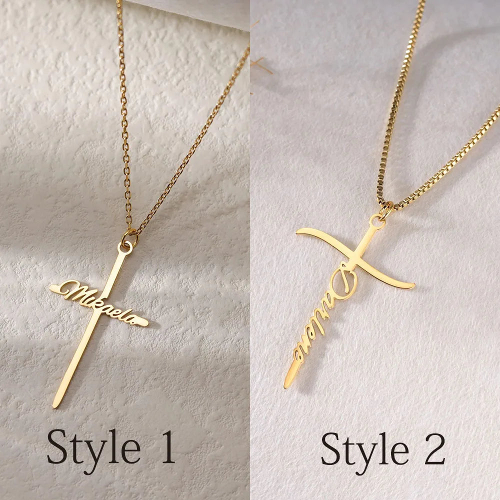 Two gold cross-shaped necklaces with 'Mia' and 'Natalie' engraved on a textured white background.