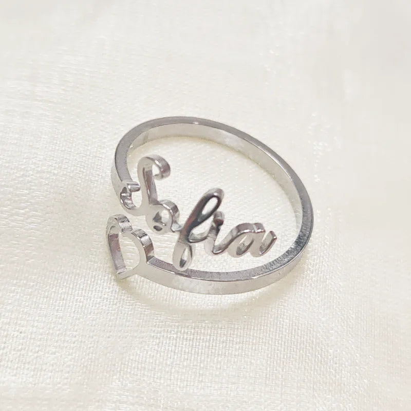 Silver ring with 'Lilia' engraved on a white fabric background