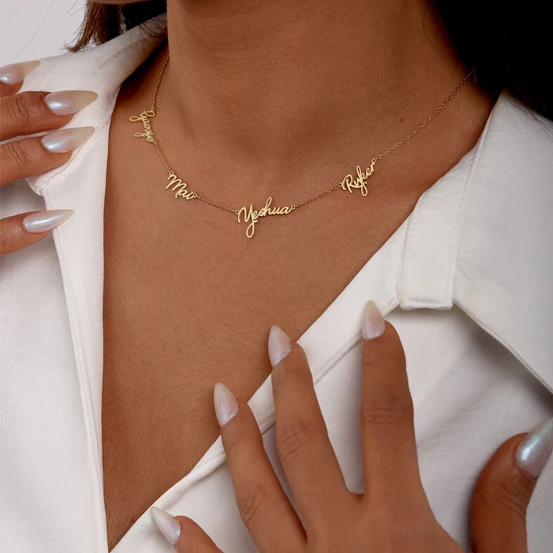Gold necklace with engraved names on a person wearing a white shirt.