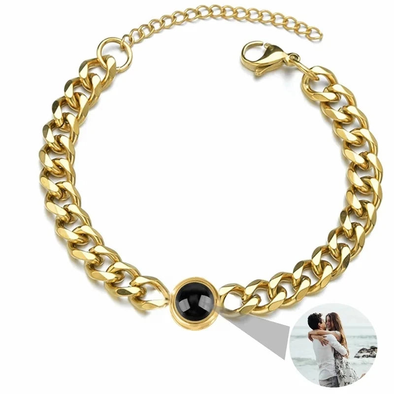 Gold chain bracelet with a black bead on a white background