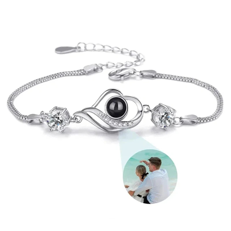 Silver bracelet with heart-shaped clasp and black gemstone on a white background